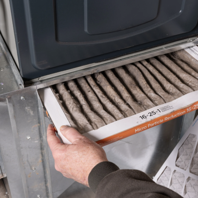 Person replacing an HVAC air filter for improved air quality and efficiency, showcasing energy-saving maintenance.