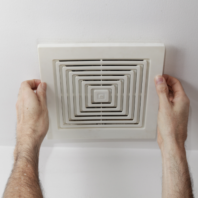 Person adjusting ceiling vent cover for proper airflow and ventilation maintenance.