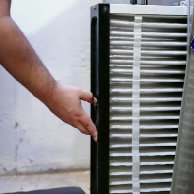 Person adjusting a Carrier air filter in a HVAC unit, showcasing maintenance and cleaning process.
