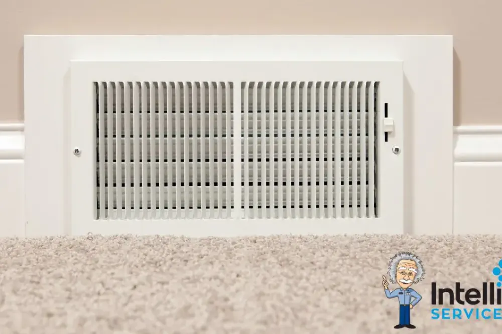 Wall vent on beige carpet in home interior, featuring Intelligent Service logo for HVAC expertise.